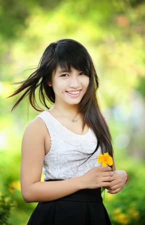 A young Thai woman in park holding a flower